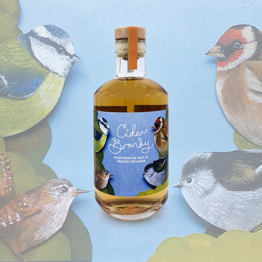 Bottle of Cider Brandy with bird illustrations on a blue background